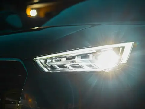 Close dos faróis iluminados de um carro à noite