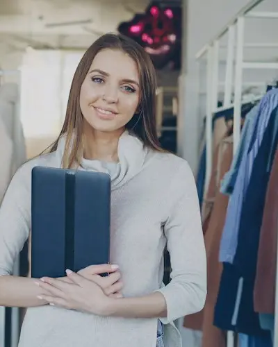 Lojista sorrindo dentro da loja de roupas